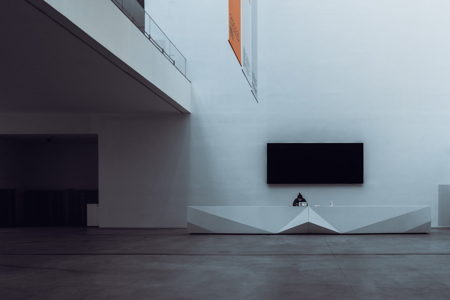 Een receptioniste zit achter een modern bureau in een bedrijfslobby.