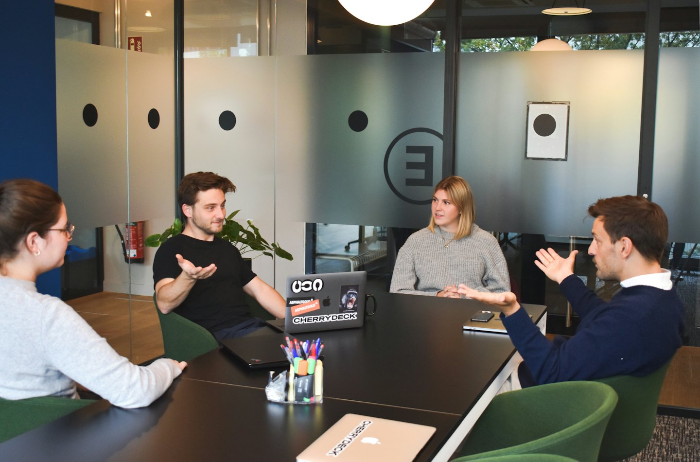 Vier professionals in een modern kantoor bespreken aan een vergadertafel.